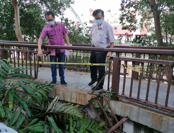 刘志良（左）指其中一扇铁制的护栏，因为腐朽掉落；右为陈劲源。