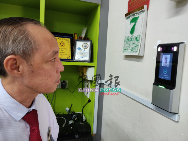 育民小学校长郑国华以人脸辨识仪，进行教职员登记。