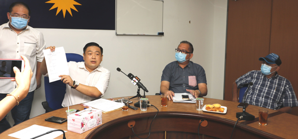 吴健南（坐者左）展示受骗者的报案书，呼吁警方尽快采取法律行动，右起为谭先生及陈中毅。