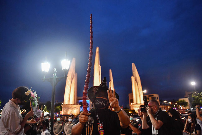 一名示威者周一打扮成《哈利波特》里面的女巫人物，以及举起《饥饿游戏》里面的反独裁“三指”手势，参与曼谷民主纪念碑的反政府集会。（法新社）