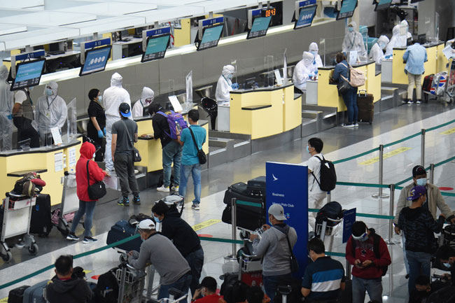 周二在马尼拉机场，柜枱后的地勤人员一律穿上防护服。（法新社）
