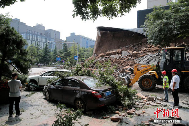 城墙坍塌下来的石块和树木砸中附近停放的汽车。