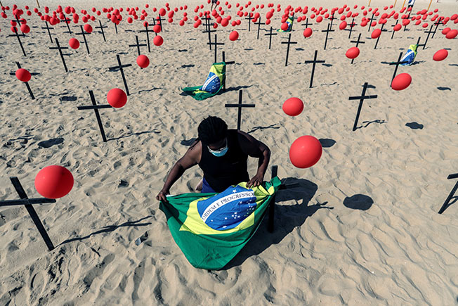 一名男子将巴西国旗绑在纪念病殁人士的红气球上。（欧新社）