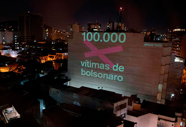 里约热内卢一栋建筑大楼墙上投射着几个大字：“博尔索纳罗手下的10万死者”。（法新社）