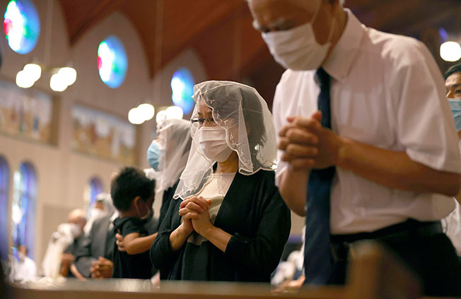 长崎浦上天主堂教徒周日戴着口罩为原爆遇难者祈祷。（美联社）