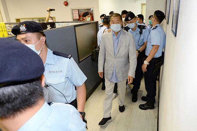 黎智英在警员押解下返回壹传媒办公室。
