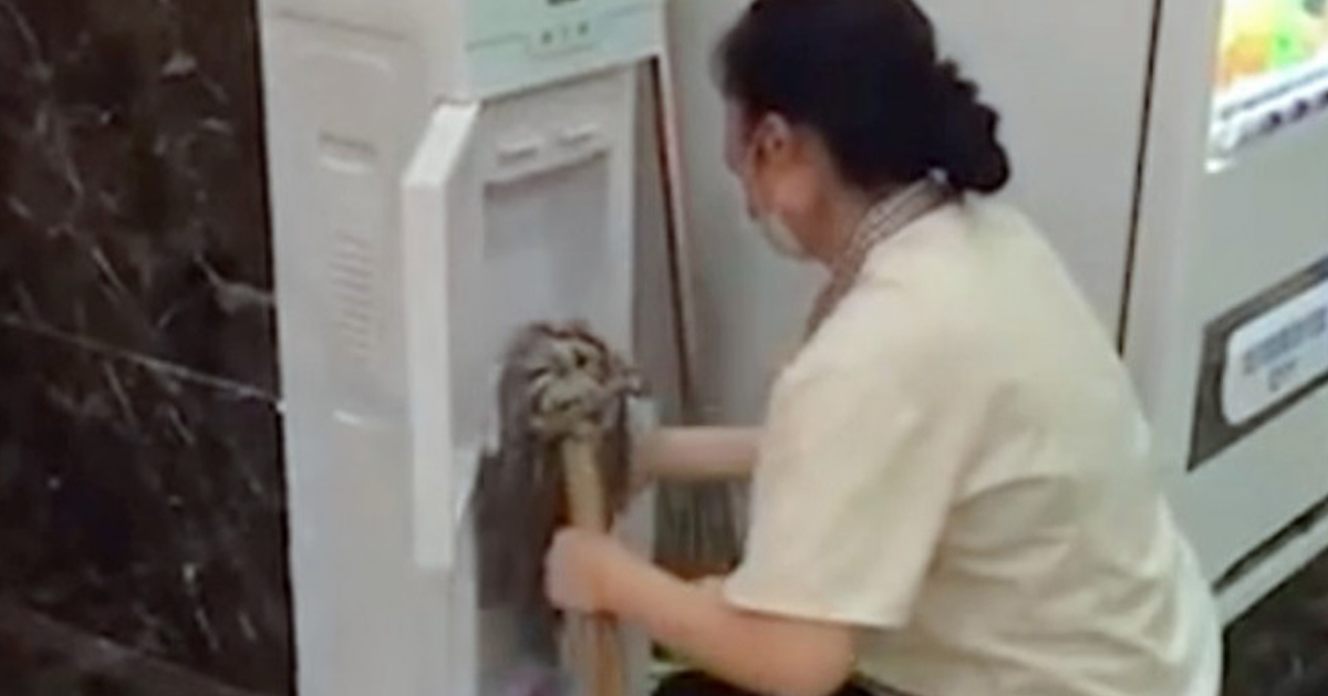 清洁工人用地拖擦拭饮水机。