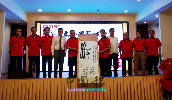陈天场（右5起）代表赠送马六甲篮总会员颜光甫的墨宝给陈江荣。