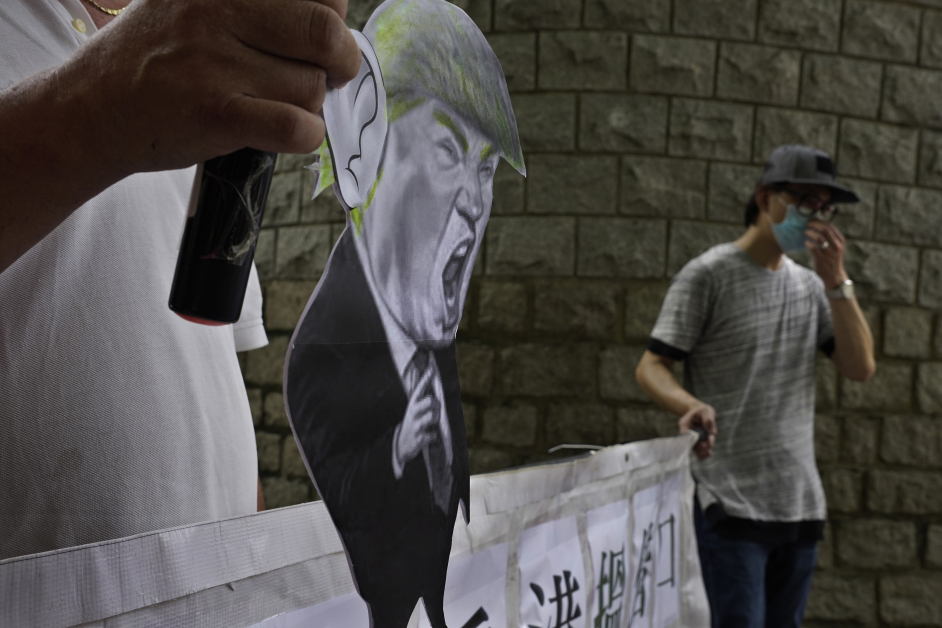  支持中国的民众在美国驻港领事馆外，举着特朗普的肖像抗议。（美联社）
