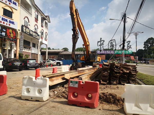 承包商在3个星期前，将挖掘机与建材搬到商店前，准备施工。