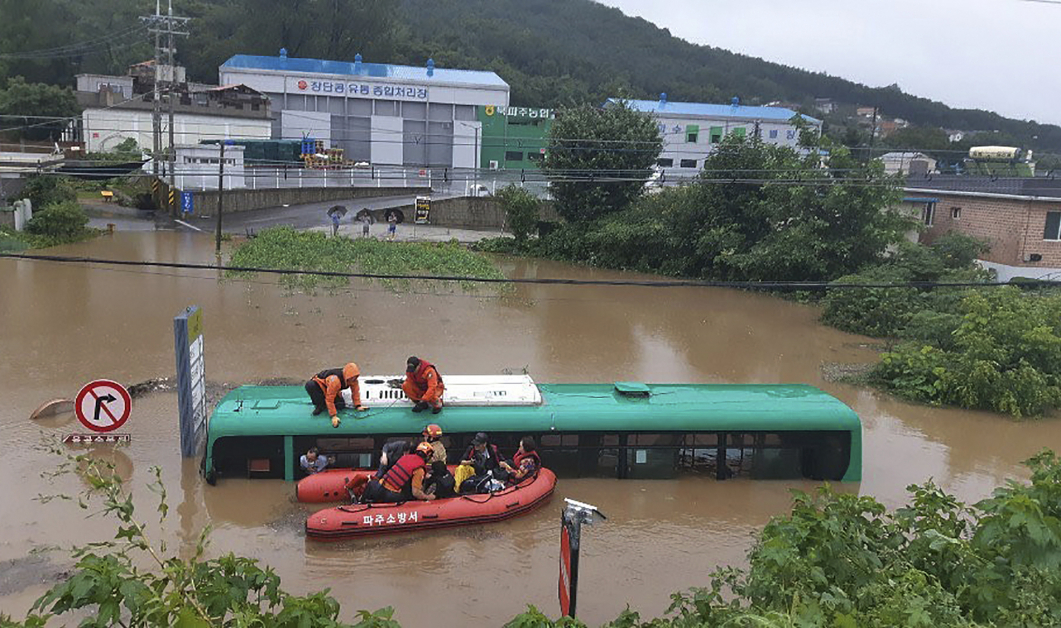韩国坡州市一辆巴士被洪水淹没，救援人员协助乘客逃生。（美联社）