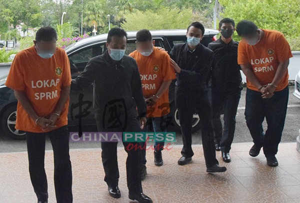 警局局长（左）及两名警员（穿橙色扣留衣）被反贪污委员会官员带上法庭，申请延长扣留令4天。