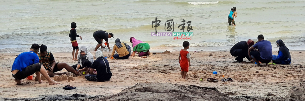 民众在海边玩沙，没有戴口罩，也没有社交距离。