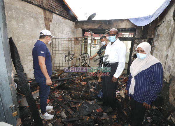 黄健文(右3)向P古拿(右2)指出被大火烧毁的睡房,屋顶已开天窗,右为嘉米拉,左为吴属神。