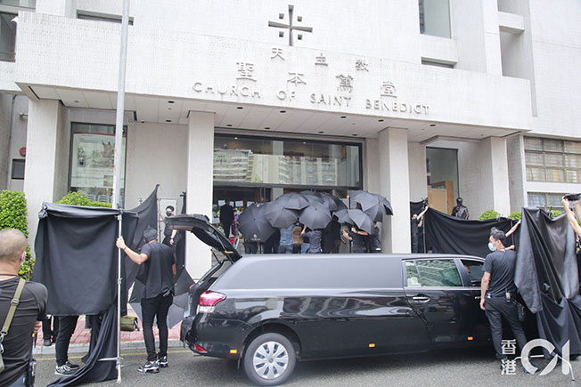 灵柩安放灵车时，数十名保安举起伞阵及黑布。