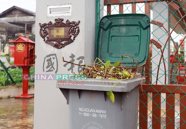 村民将树枝杂草与垃圾一同处理，塞入垃圾桶。