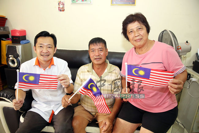 等了超过一甲子才获批公民权，成为真正大马人，张金销（中）与谢琪清（左）及太太邱金梅一起挥动国旗，欢庆“马来西亚日”。