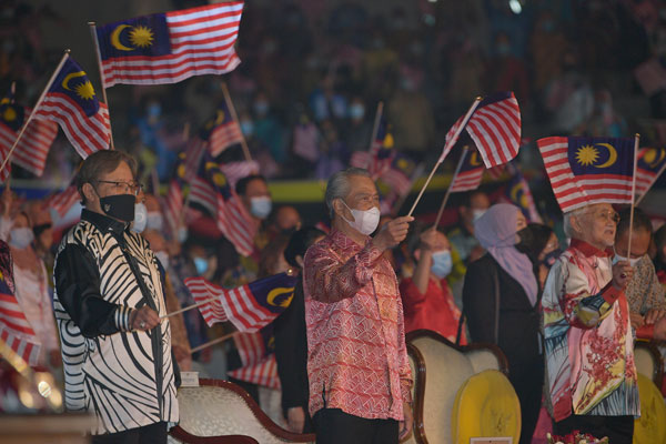 阿邦佐哈里（左起）、慕尤丁和泰益马目挥动国旗，同庆马来西亚日。（马新社）