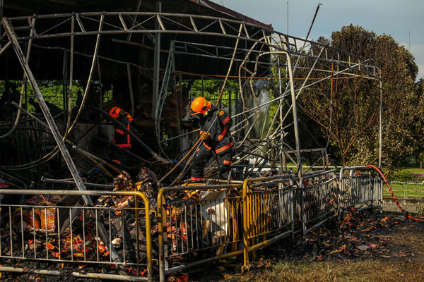民防人员周六下午在烧坏的帐篷区调查。