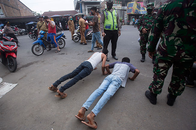 周三在印尼棉兰，违反防疫规定的男子被官员处罚掌上压。