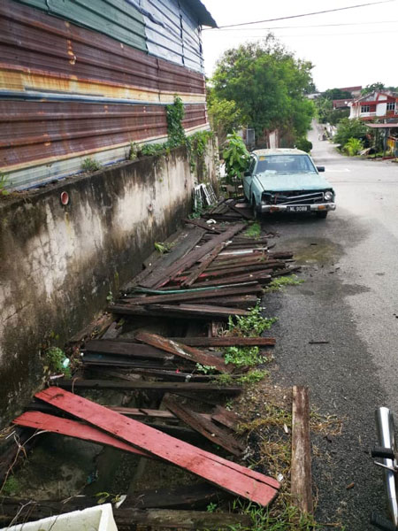 亚沙新村一户居民霸占邻居的沟渠处，架起木条停泊废车。
