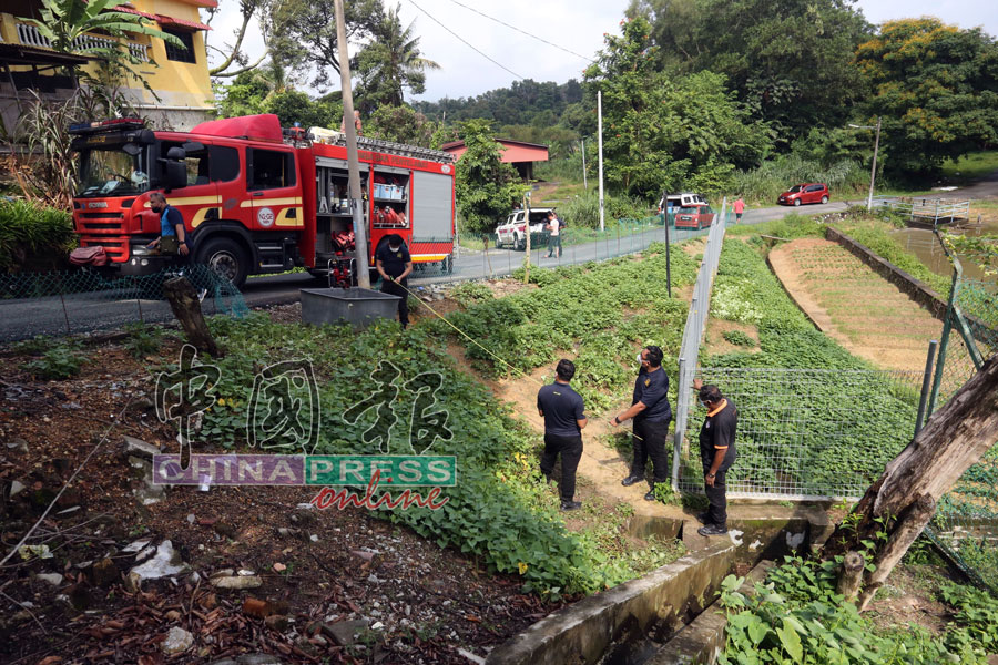 警员及消拯员在联手调查死者杨品南如何失足掉入菜圃旁的暗涵。