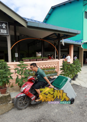 村民乘坐摩哆将垃圾桶拖回家。