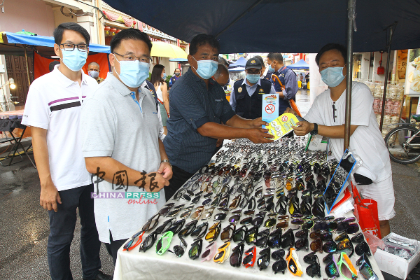 陈炜建（左起）、颜天禄及拉末马里曼分派禁烟宣传手册给鸡场街夜市小贩。