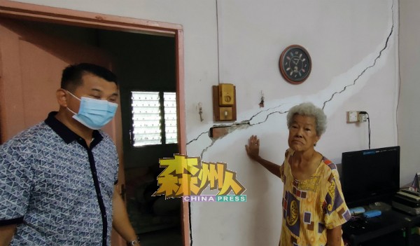 78岁的唐亚妹看着自己住家墙壁裂缝处处,一脸无奈,左为杨孔耀。