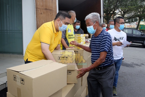 陆兆福(左)亲自协助文丁新村村长杨谭顺(左2),搬动装有月饼礼盒箱子。