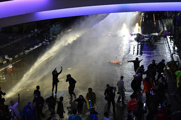 面对含催泪液体的水炮，示威者不得不走避。