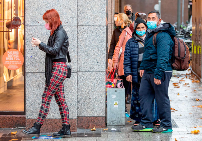 周一在爱尔兰都柏林，人们在一家服装店前排队等候，保持社交距离。（法新社）