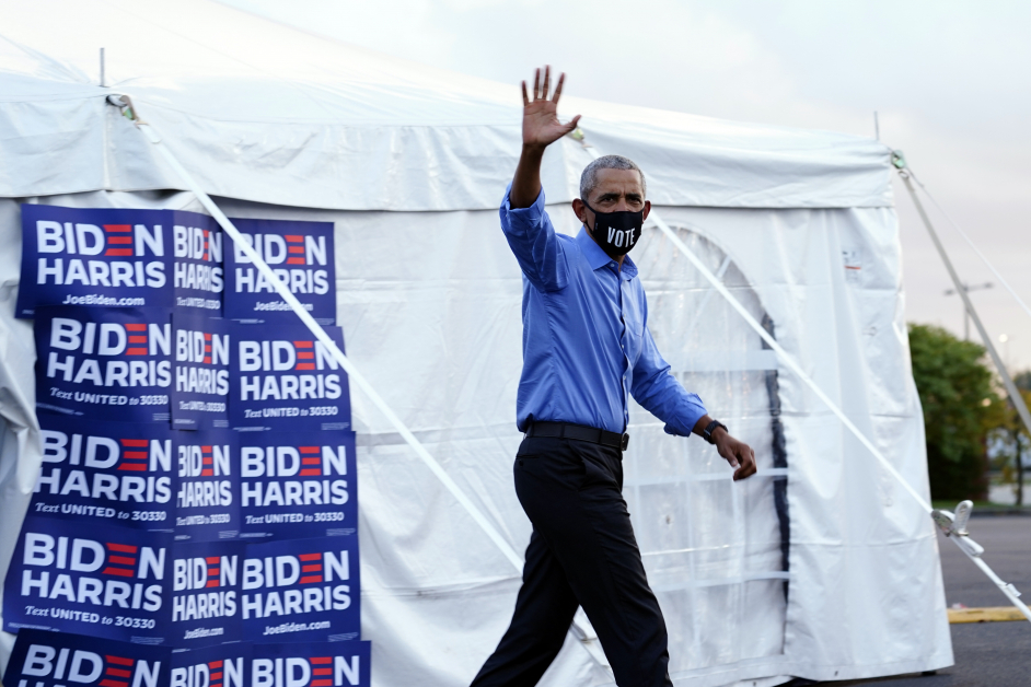 奥巴马戴着口罩抵达竞选集会现场， 并向群众挥手致意。（美联社）