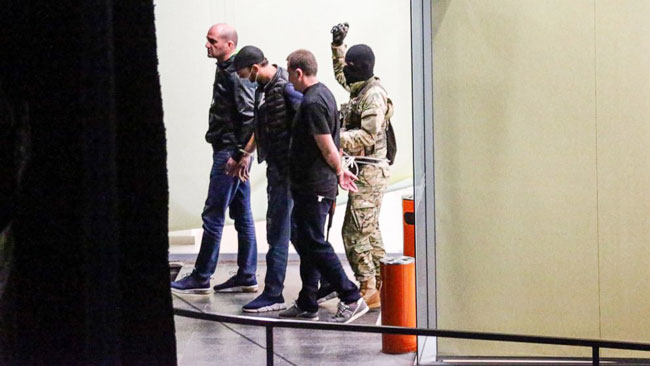 蒙面军装枪手挟持3名男子离开银行的画面。
