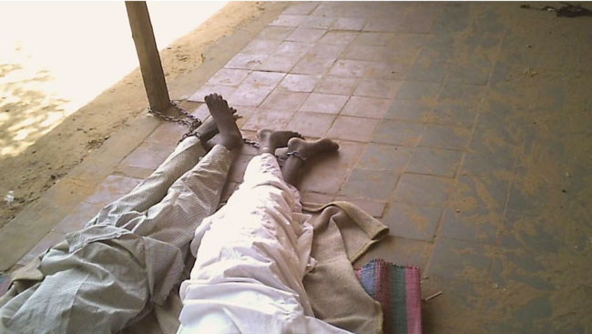 学童双脚被铁链锁住睡在地面。
