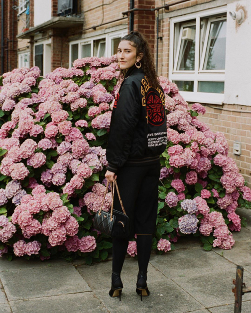 在Burberry担任数码设计工作的Emily穿2021早春刺绣棒球外套与及膝裙在位于Bethnal Green自家门口拍型录。