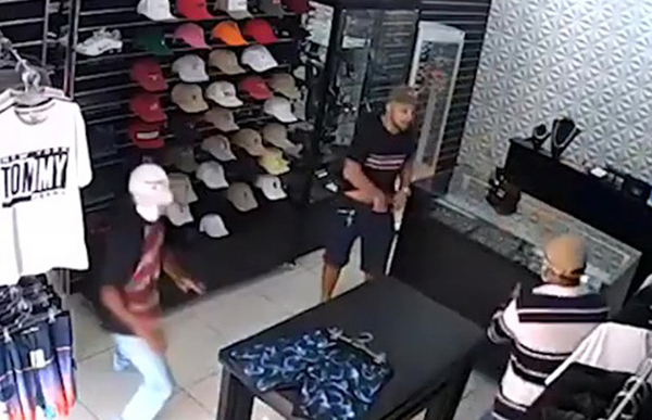 店老板（褐色衫戴帽者）从柜台后步出及掏枪击退劫匪。