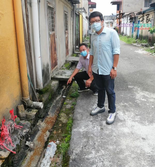 叶汉良（左起）及李春源巡视新马六甲花园商店后巷水沟阻塞的情况。