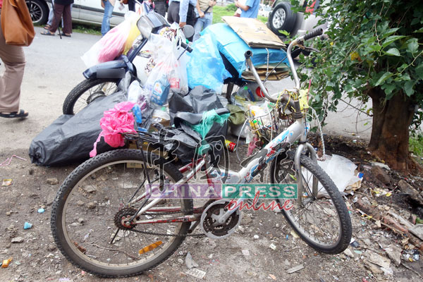 曾女士收取环保回收物品时所使用的脚踏车及摩哆。