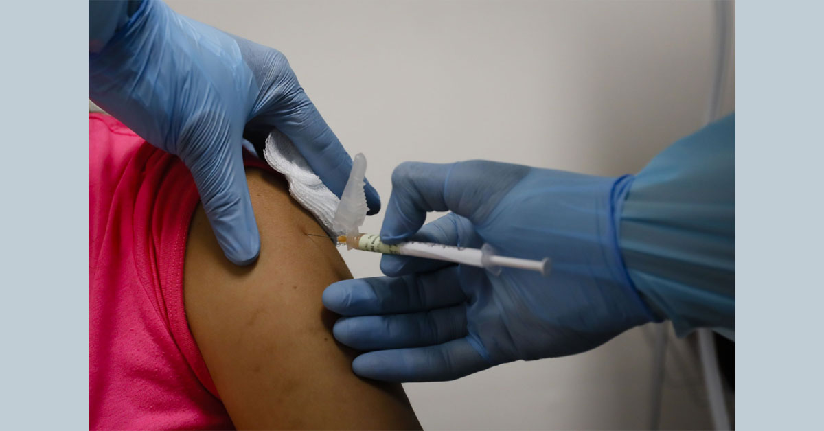 分析员预测，新冠疫苗接种将为手套业捎来新商机；图为美国佛罗里达州一间研究中心，一名卫生官员为一名进行临床试验的妇女注射新冠疫苗。
