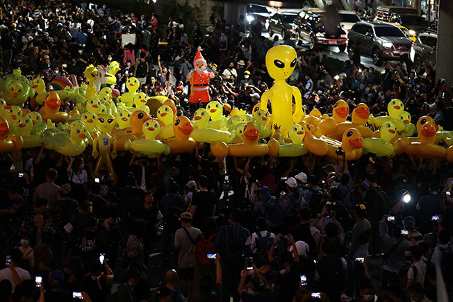 民众在头上传递一批黄色吹气鸭子。（法新社）