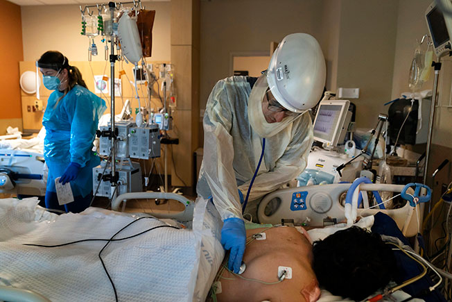 在美国洛杉矶普罗维登斯圣十字医疗中心，身穿防护服的医生在照顾新冠肺炎患者。（美联社）