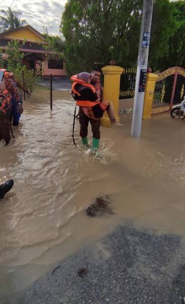 消拯员抱起灾黎离开水灾区，再送到疏散中心。