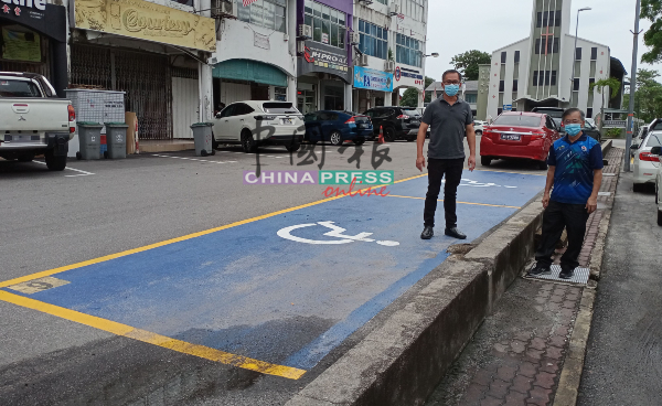 残障人士泊车位位置不恰当，泊车后司机座旁就是较路面低的人行走道，左起为刘志俍及其助理陈劲源。