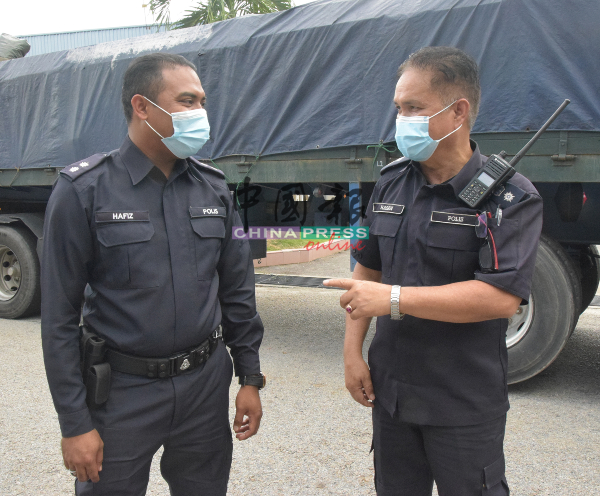交警警官哈菲兹（左）哈山峇斯里汇报取缔行动进展。