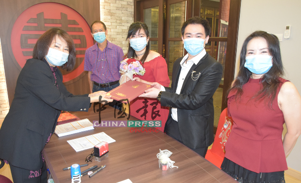 黄美妹（左）颁发结婚证书给一对新人。右起是黄秀玥、陈玟企、郑淑仪及郑忠成。