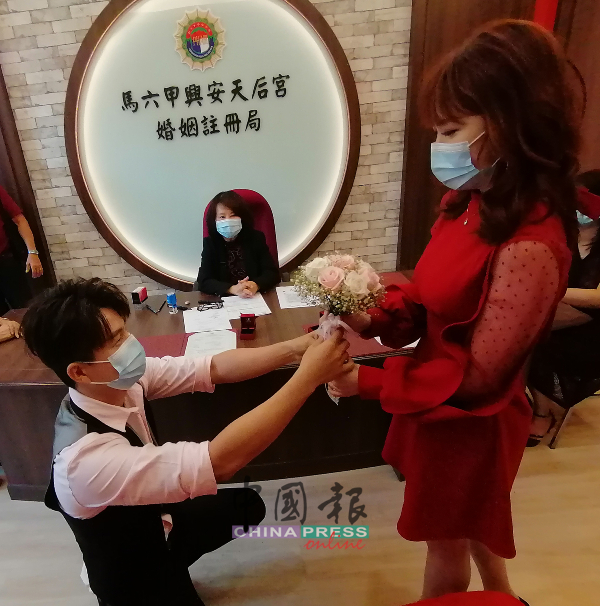 吴满闻（前左）于11时11分，单膝下跪献花给太太李诗颖，由黄美妹见证。