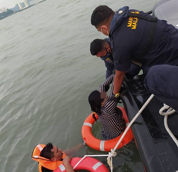 海事局官员将在海上漂浮的女子及辅警，救上快艇。