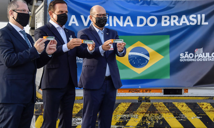巴西圣保罗州州长多利亚(中)展示运抵当地的中国疫苗。