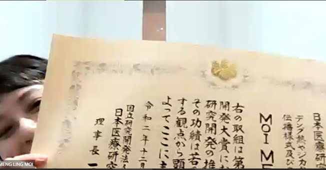 梅敏苓展示日本医疗研究发展机构颁发的医药研究奖的奖状。